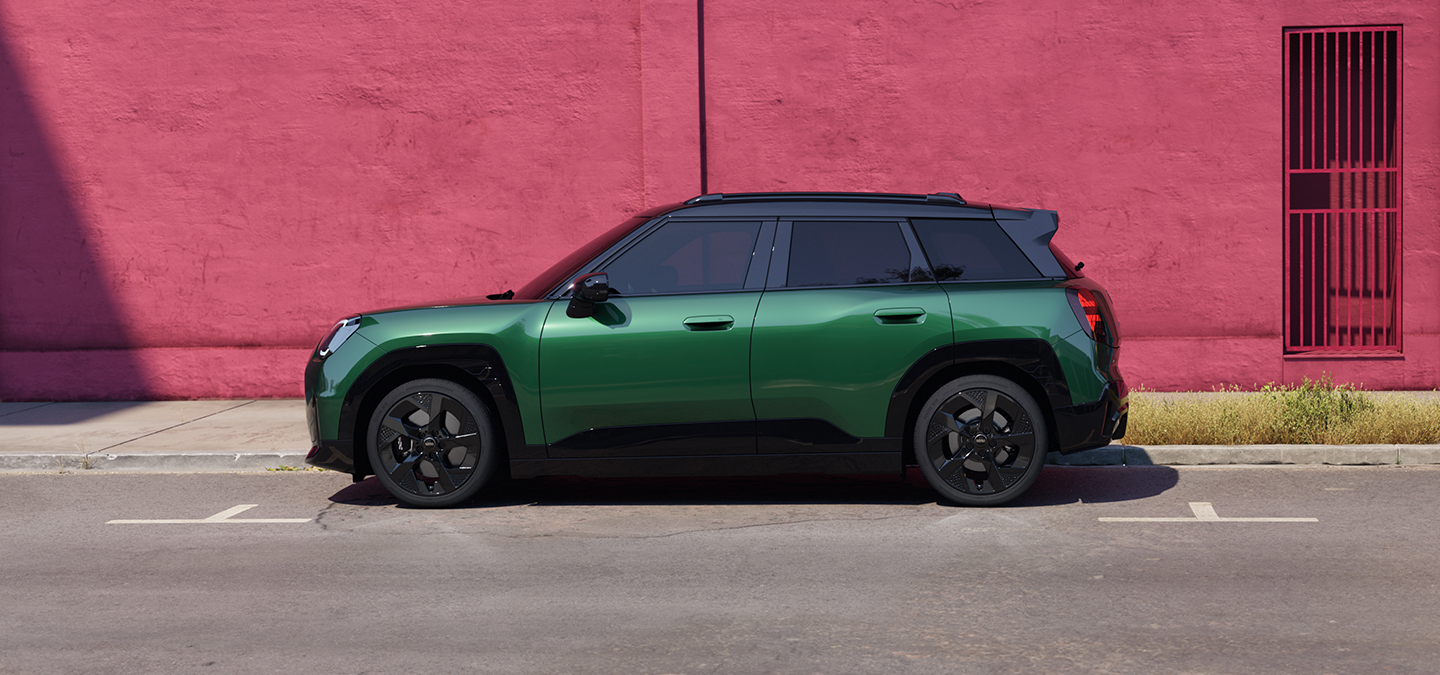 Boční pohled na elektrické MINI Aceman v zelené barvě British Racing Green s černou střechou na ulici.