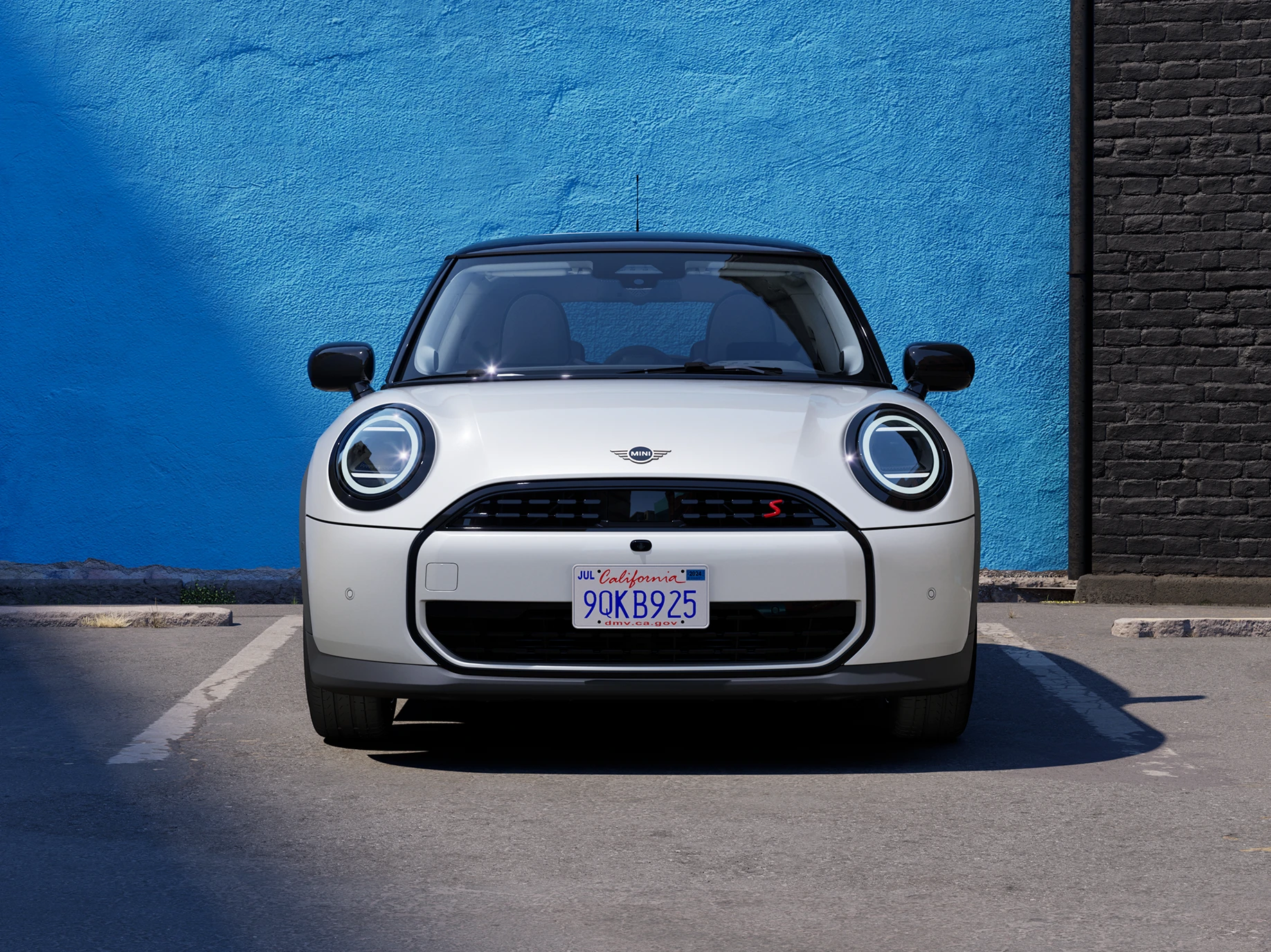 Pohled zepředu na zaparkované MINI Cooper v bílé barvě Nanuq White s černou střechou.