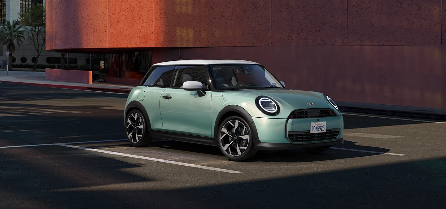 Boční pohled zepředu na MINI Cooper v zelené barvě Ocean Wave Green a bílou střechou.