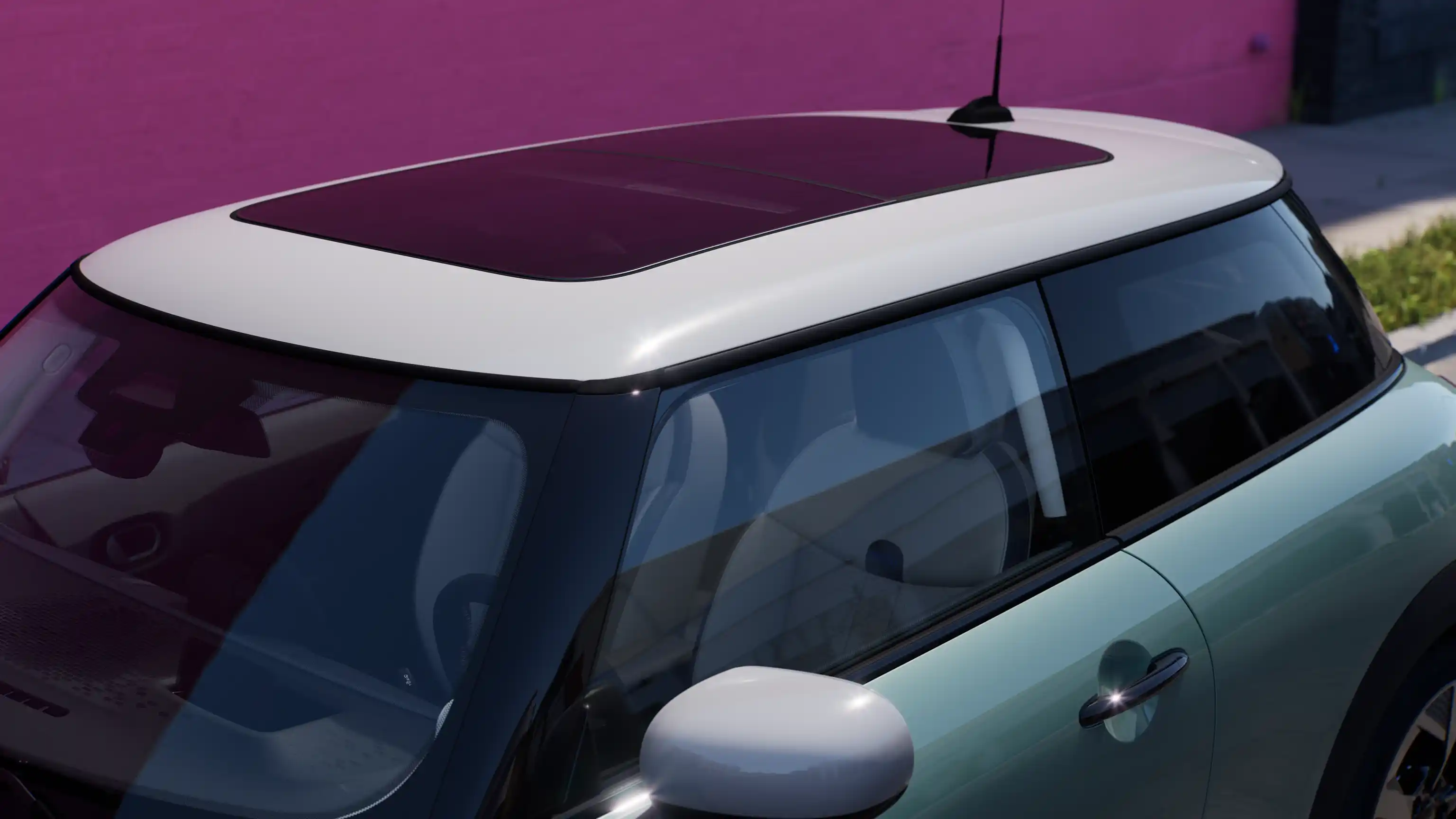 Pohled shora na MINI Cooper v zelené barvě Ocean Wave Green s kontrastní střechou a velkým skleněným střešním oknem.