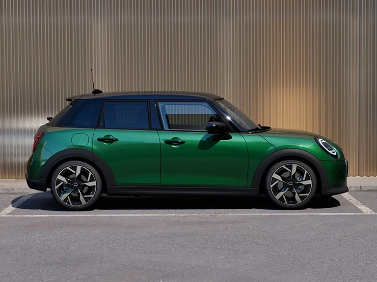 Boční pohled na zaparkované 5dveřové MINI Cooper v zelené barvě British Racing Green s černou střechou.