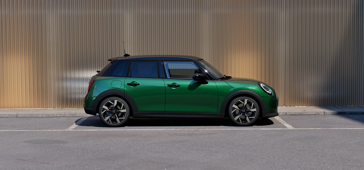 Boční pohled na zaparkované 5dveřové MINI Cooper v zelené barvě British Racing Green s černou střechou.