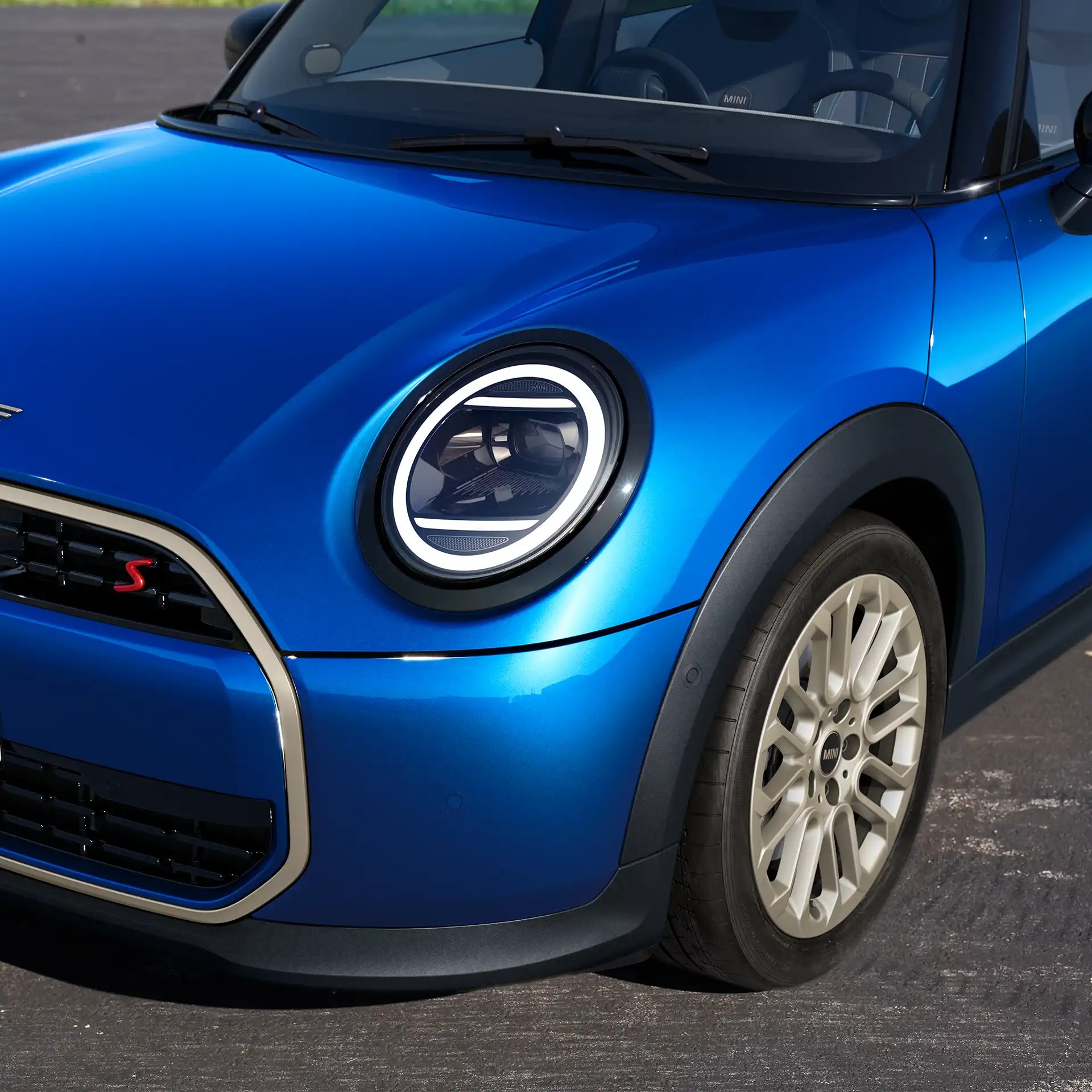 Detailní pohled na přední část vozu 5dveřového MINI Cooper s designovými prvky, světlomety a ráfky kol.