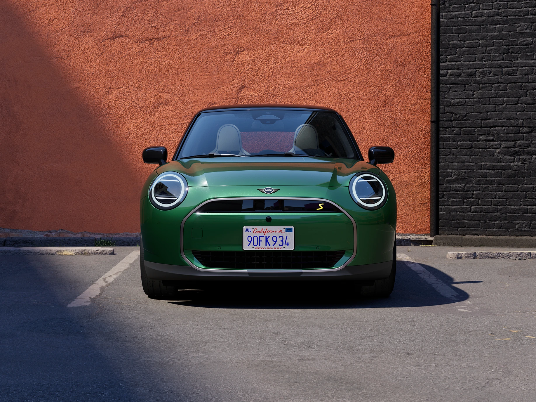 Pohled zepředu na elektrické MINI Cooper v zelené barvě British Racing Green s černou střechou.