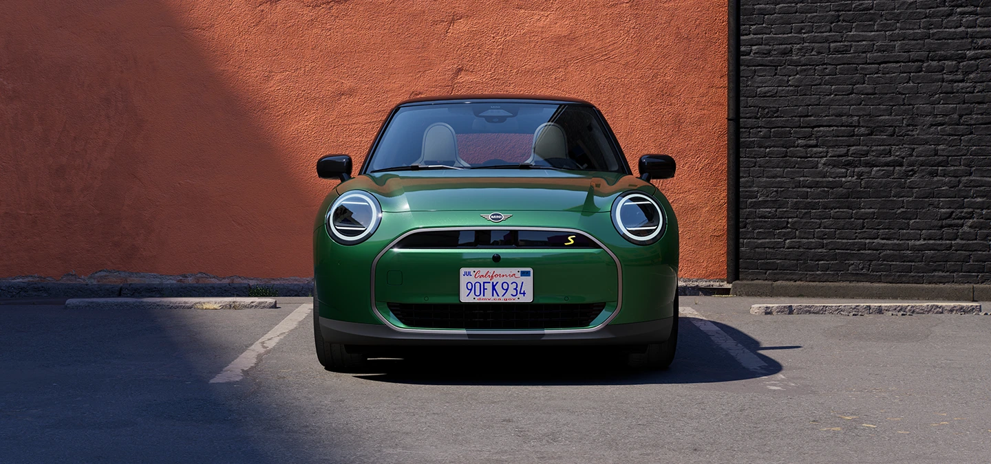 Pohled zepředu na elektrické MINI Cooper v zelené barvě British Racing Green s černou střechou.