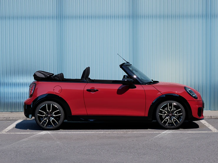 Boční pohled na MINI Cooper Cabrio v červené barvě Chili Red na ulici.