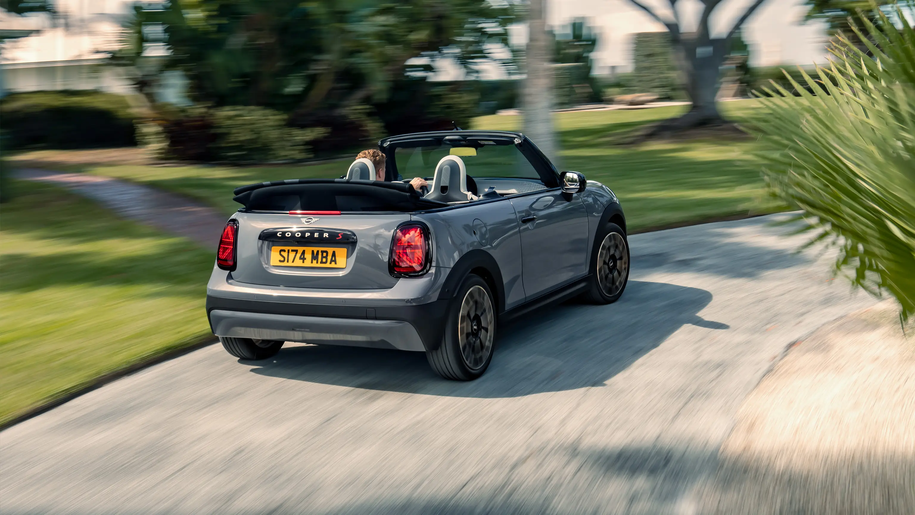 Pohled zezadu na jedoucí MINI Cooper Cabrio v šedé barvě Copper Grey