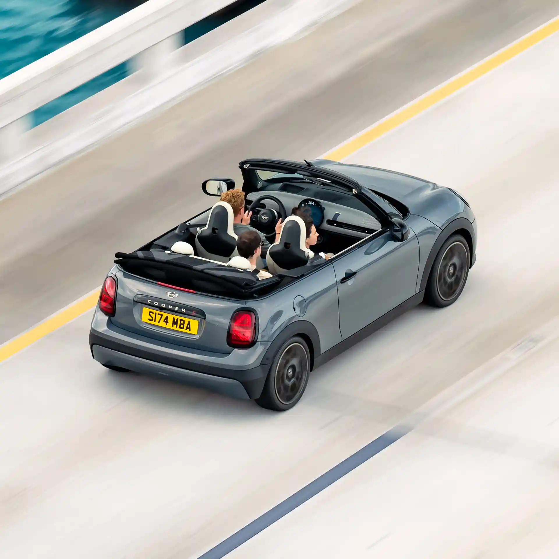 Pohled zezadu shora na MINI Cooper Cabrio jedoucí po ulici