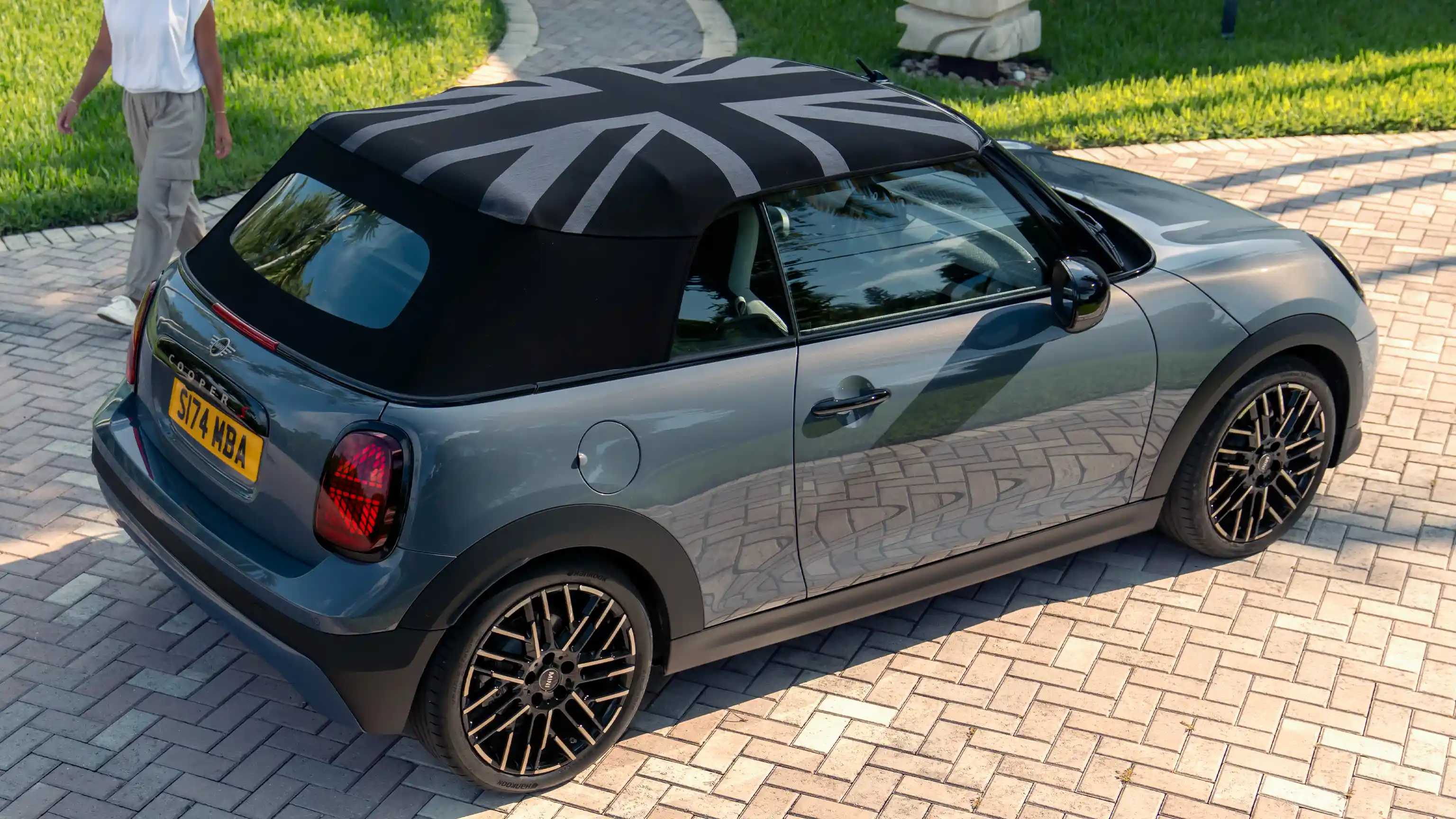 Pohled z boku na MINI Cooper Cabrio v šedé barvě Copper Grey se střechou MINI Yours