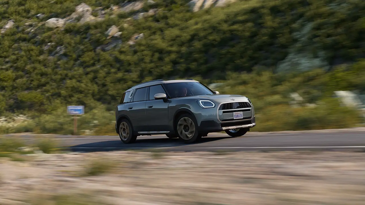 Pohled na MINI Countryman v zelené barvě Smokey Green s paketem Favoured při jízdě v terénu