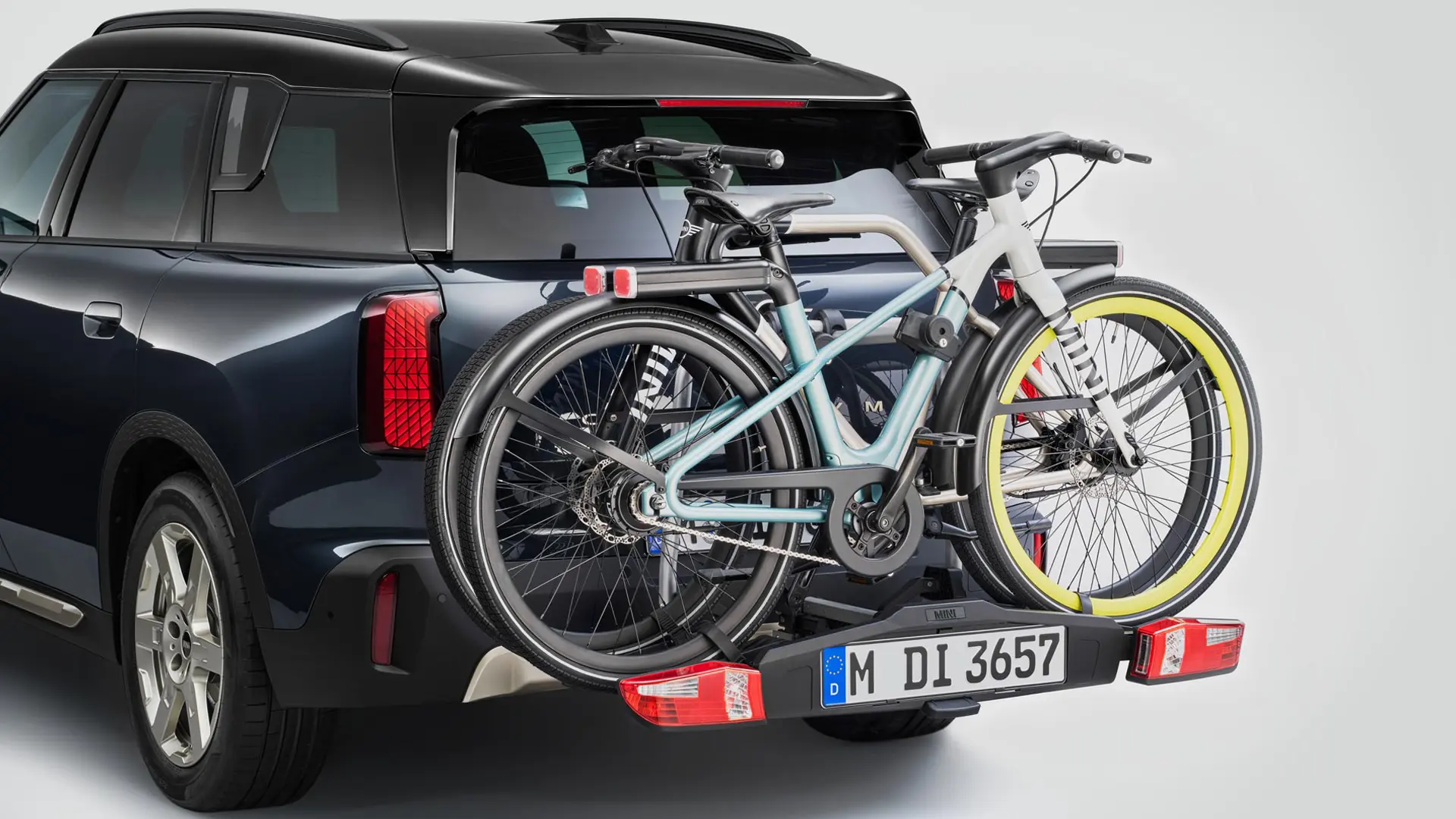 MINI Countryman v černé barvě vybavené zadním nosičem kol se dvěma horskými koly, pohled zezadu.