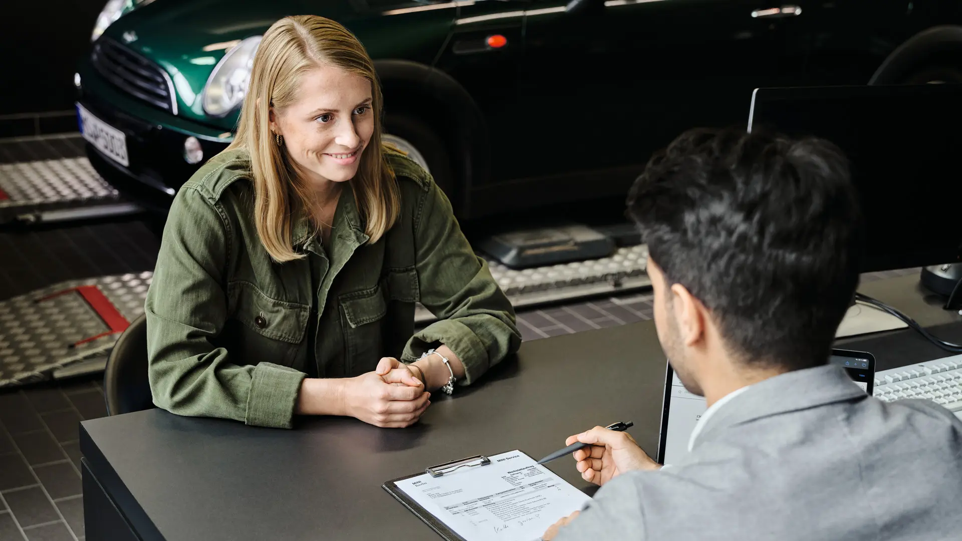 MINI Centrum s konzultantem, který radí zákaznici o jejích možnostech servisu, oba sedí u stolu.