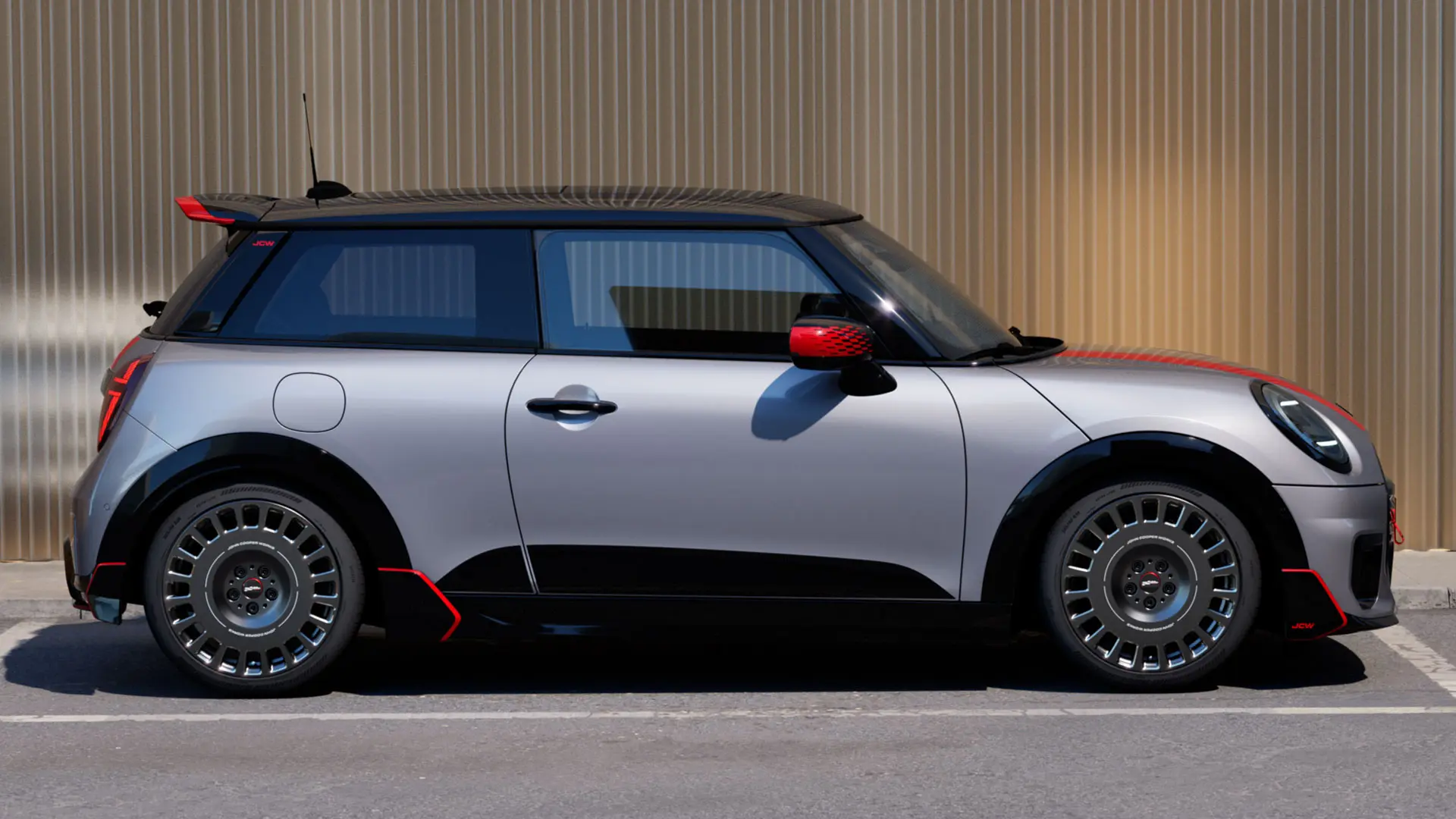 3dveřové MINI Cooper ve stříbrné barvě Melting Silver s John Cooper Works střešním spoilerem vylepšujícím aerodynamické vlastnosti – pohled z boku.