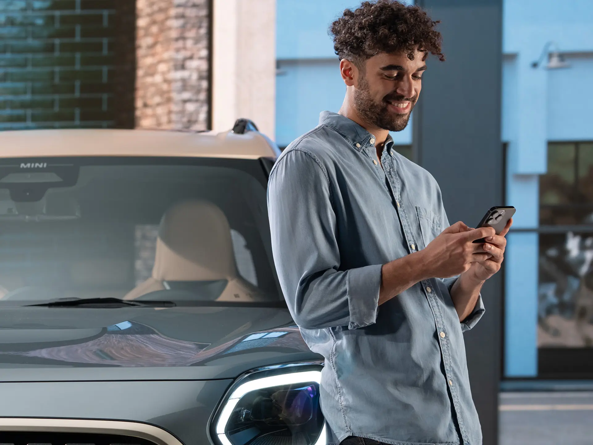 MINI personalizované servisní schůzky - muž stojící vedle MINI píše na telefonu