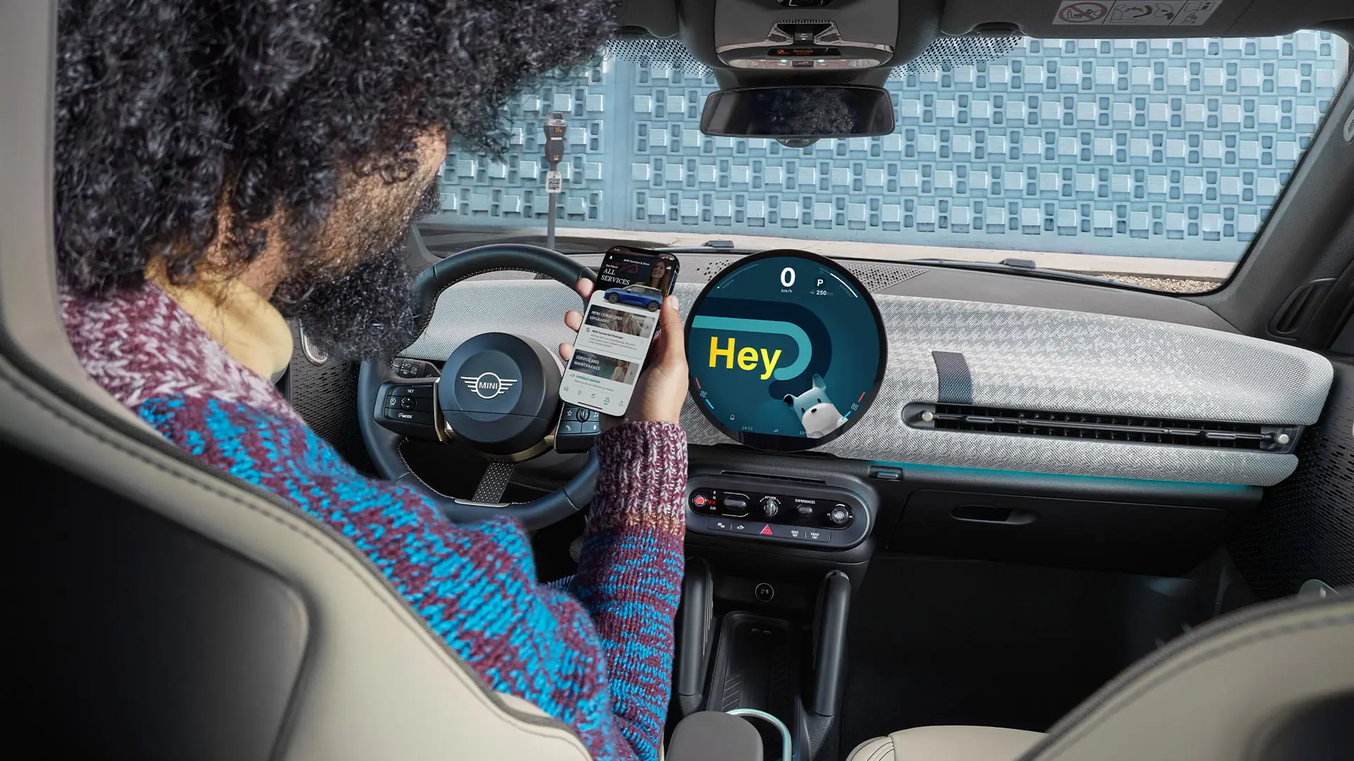 Muž sedící v MINI a dívající se na svůj telefon.