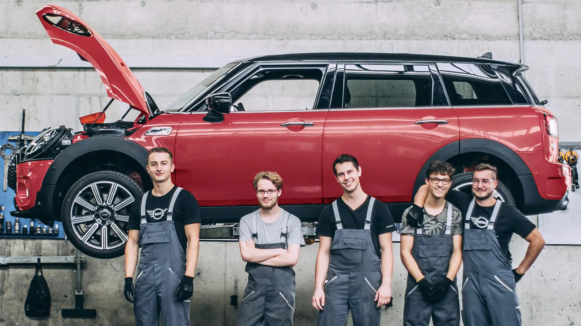 Pracovníci MINI servisu před vozem MINI Countryman na zvedáku.