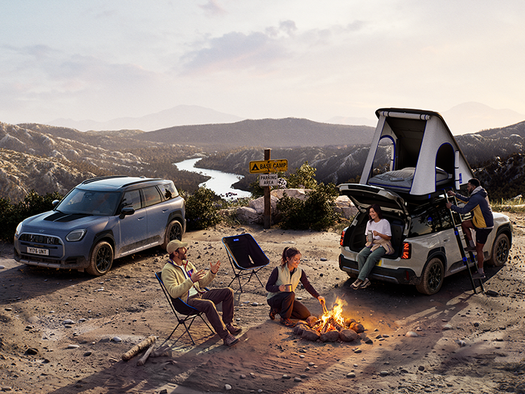 Fotografie dvou MINI Countryman Untamed Edition na hoře při západu slunce.